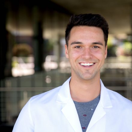Male Student in White Labcoat Looks at Camera and Smiles Opportunities Welcome to Sites.Dot