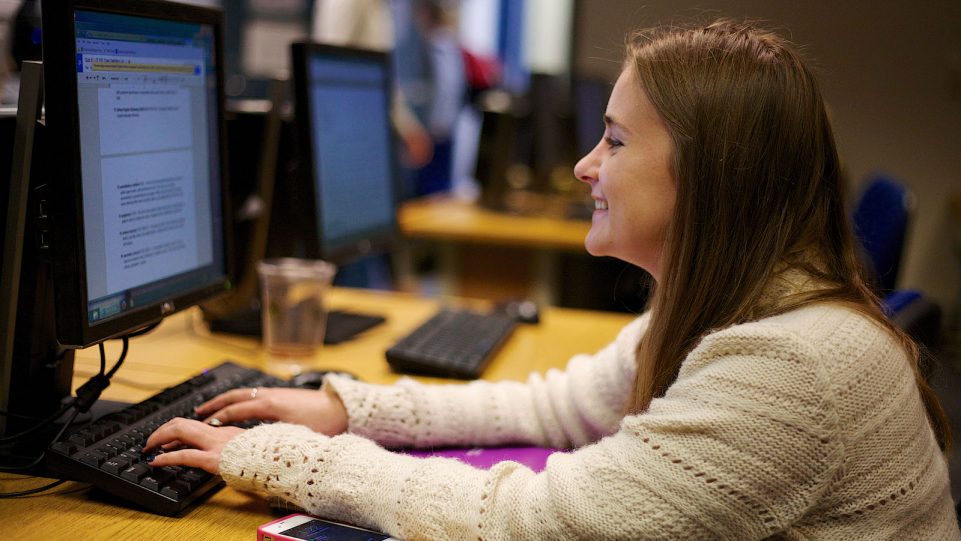 Female Student Sitting at a PC Workstation in the Computer Lab